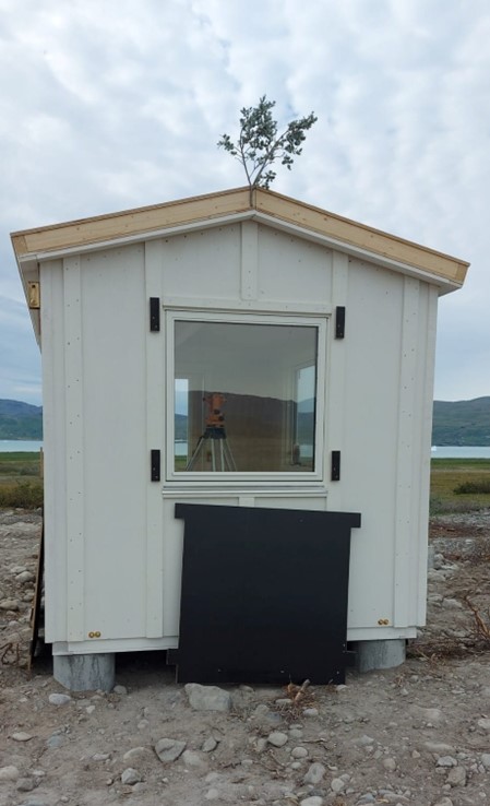 One of the finished magnetometer houses, adorned with a local bit of foliage as part of the rejsegilde. (DTU Space-Klaus Nielsen)