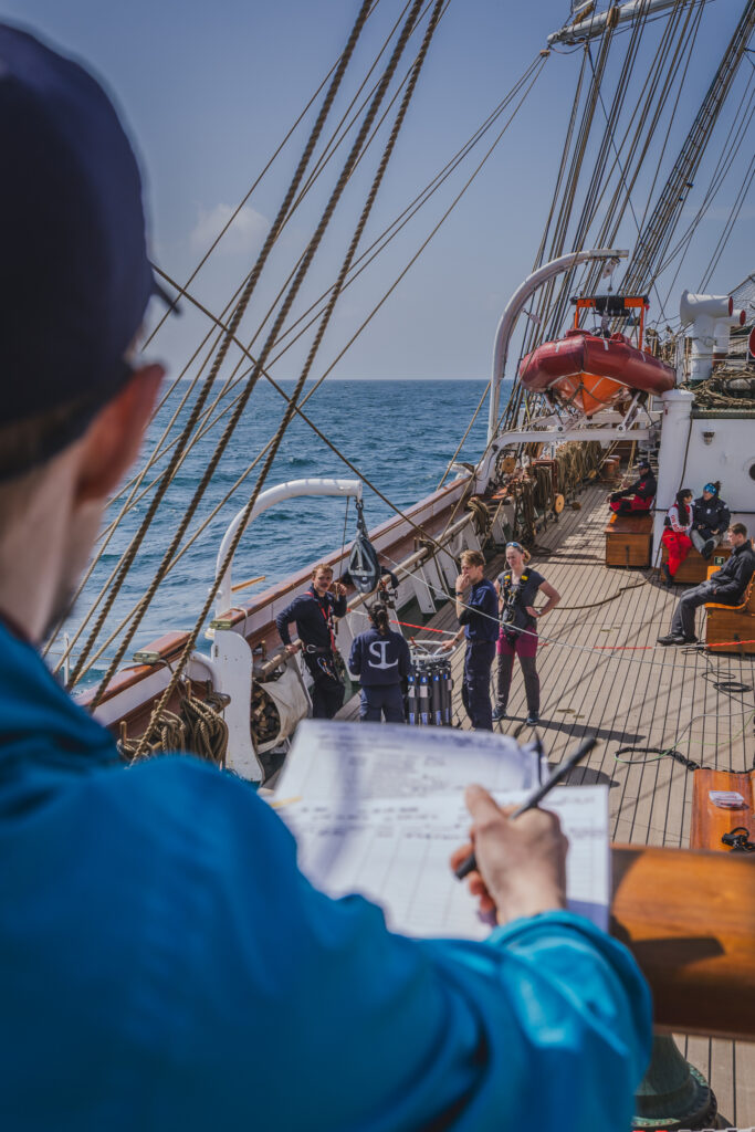 The station manager oversees the CTD deployment process from the upper deck, ensuring that all procedures are followed safely and smoothly as students coordinate the operation below. (Ocean Media Lab)