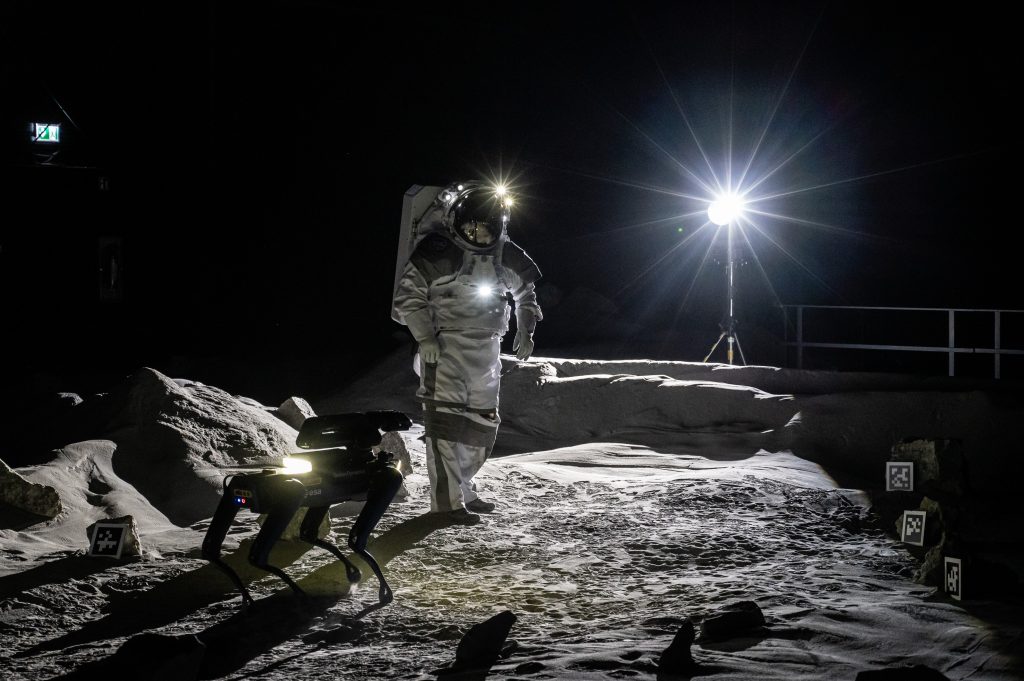 An astronaut and robot dog Spot in the LUNA facility. Credit: ESA/DLR