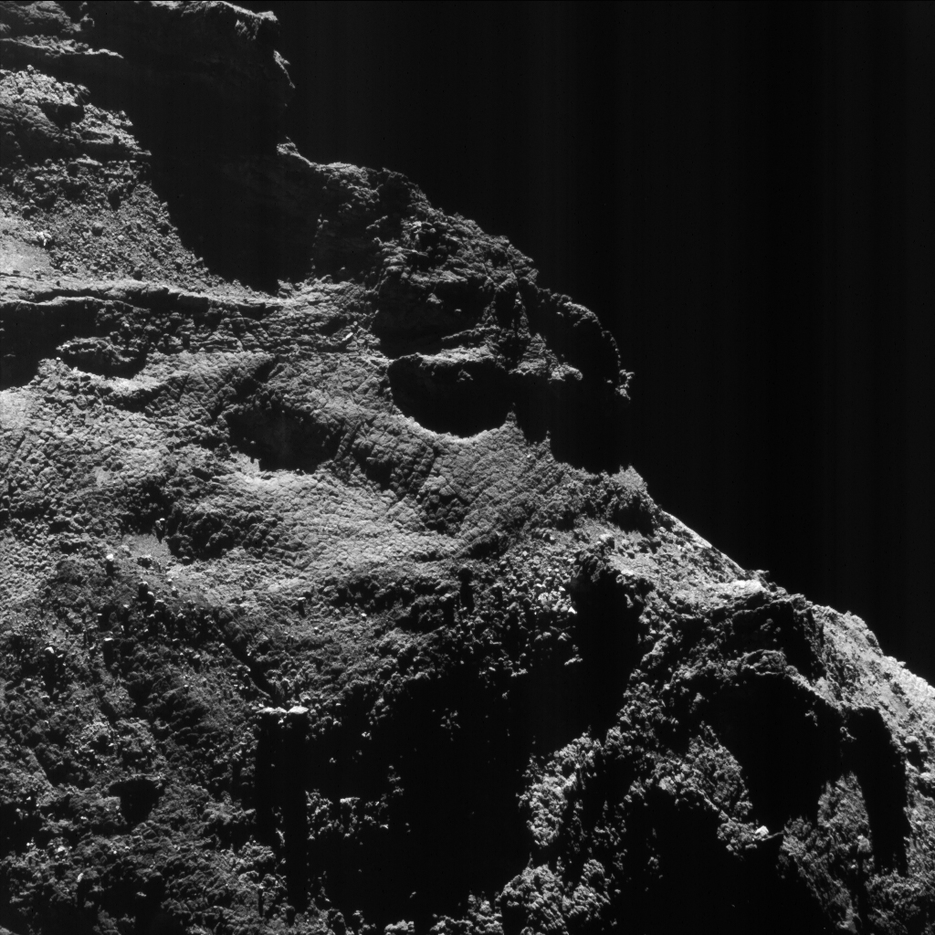 Enhanced NAVCAM view of Comet 67P/Churyumov-Gerasimenko, taken from a distance of 9.7 km on 24 July 2016. The image scale is 0.8 m/pixel and the image measures 0.9 km across. The faint vertical striping effect, especially visible in the upper right part of this view, is an image artifact. Credits: ESA/Rosetta/NAVCAM – CC BY-SA IGO 3.0
