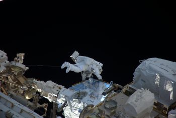 Thomas in same white spacesuit holding onto handrail during his first spacewalk. Credits: Roscosmos